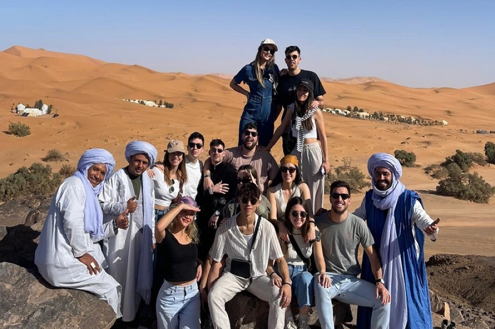 Grupo de viajeros con guías bereberes sobre una duna del desierto de Marruecos