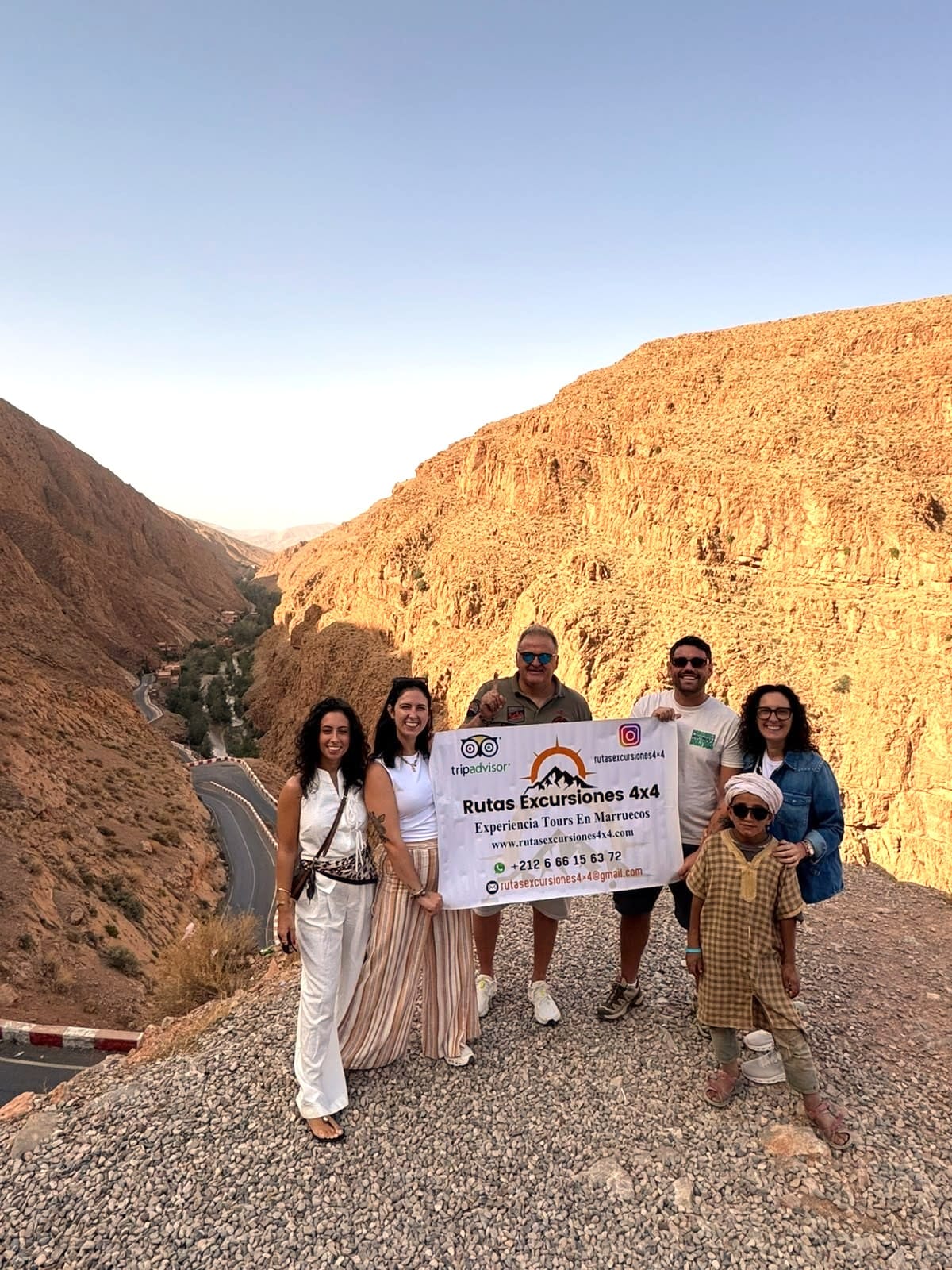 Grupo de viajeros con la bandera de Rutas Excursiones 4x4 en el valle de Todra